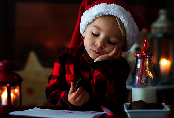 Weihnachtsfotoideen: Familie, Freunde, Haustiere – zauberhafte Erinnerungen schaffen! Kleinkind mit Weihnachtsmütze und Brief an den Weihnachtsmann. Fotoideen Weihnachten entdecken.