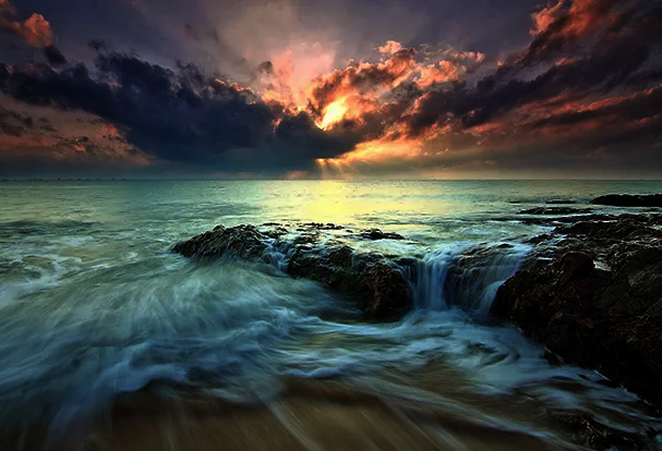 Fotografie Tipps – Graufilter kurz erklärt Abendstimmung am Strand mit Felsen und sanft fließendem Wasser. Durch den richtigen Einsatz eines Filters wirkt das Wasser seidig und elegant. Fotografie Tipps für atemberaubende Aufnahmen am Meer.