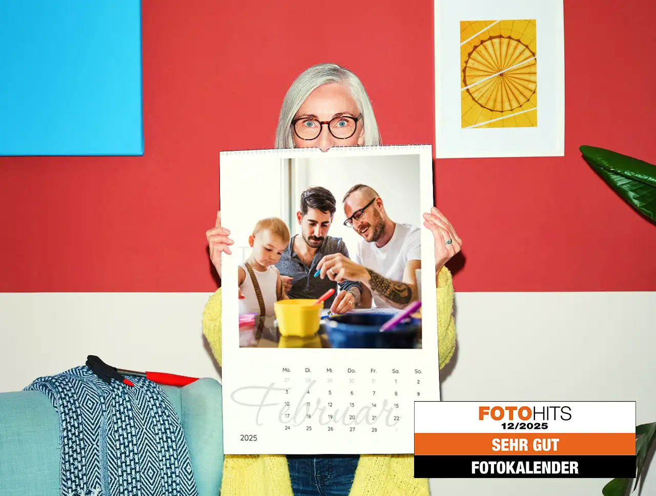 Ein Fotokalender, Terminkalender mit mehreren Spalten Eine weißhaarige Frau im gelben Strickmantel hält einen großen Terminkalender vor sich, der zeigt, wie du deinen Fotokalender selbst gestalten könntest.