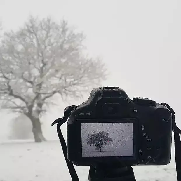 Eine Kamera auf einem Stativ beim Fotografieren im Schnee. Dabei können Kälte und Nässe eine Herausforderung darstellen.