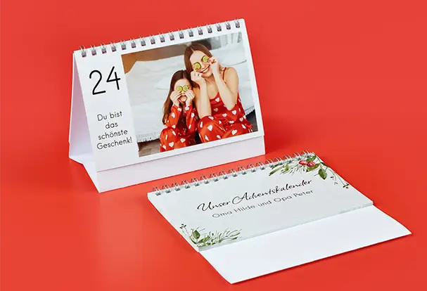 Zwei Tischadventskalender, einer flach und der andere aufgestellt, sind mit festlichem Design und eigenen Fotos bedruckt. Diese personalisierten Fotogeschenke Weihnachten bringen täglich Freude und schaffen eine besondere Atmosphäre während der Adventszeit.