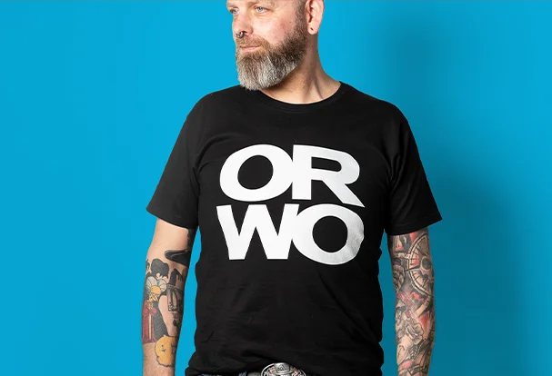 ORWO-Merchandise in Aktion: Ein junger Mann trägt ein schwarzes T-Shirt mit weißem ORWO-Logo – schlicht, modern und perfekt für echte Fans der Marke. FAQ ORWO Fotogeschenke