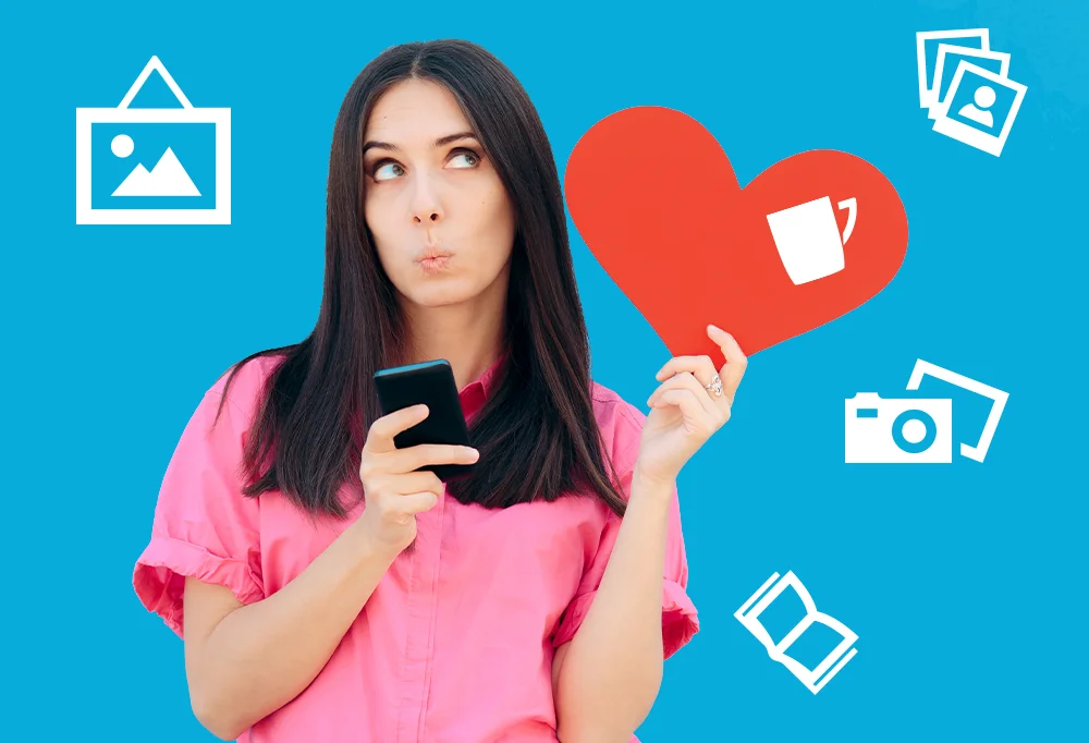 Fotoprodukte zum Valentinstag entdecken Frau in pinkem Shirt hält ein Smartphone und ein rotes Herzsymbol in der Hand, umgeben von Icons für Bilder, Kamera, Tasse und Fotobuch – kreative Fotoprodukte und Fotogeschenke zum Valentinstag