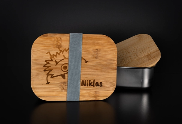 Personalisierte Lunchbox – Black Week Rabatte Diese Lunchbox aus Metall kommt mit einem gravierten Holzdeckel, der ein kleines Monster und den Namen Niklas zeigt. Ideal für die Pause und ein tolles Fotogeschenk. Erhältlich in den Black Week Rabatten.