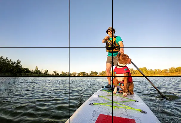 Mit dem Hund und dem Board auf dem See. Was braucht es mehr? Ein Stand-Up-Paddler genießt das schöne Wetter. Der Bokeh-Effekt fehlt hier, aber der Goldene Schnitt ist eingezeichnet.