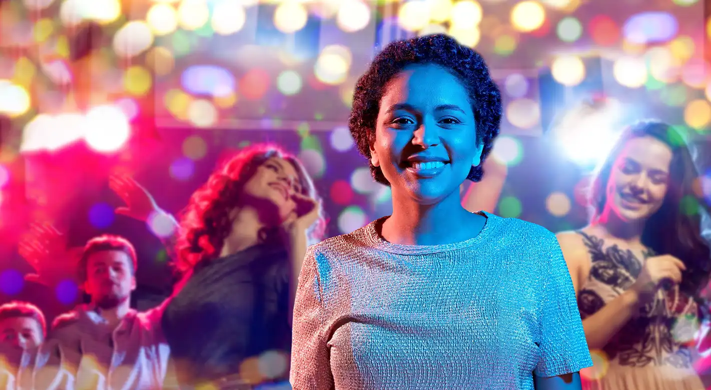 Eine Frau trifft sich mit Freundinnen zur sommerlichen Partynacht. Im Hintergrund ist ein kunterbuntes Lichtermehr, welches durch den Bokeh-Effekt die ausgelassene Stimmung unterstreicht.