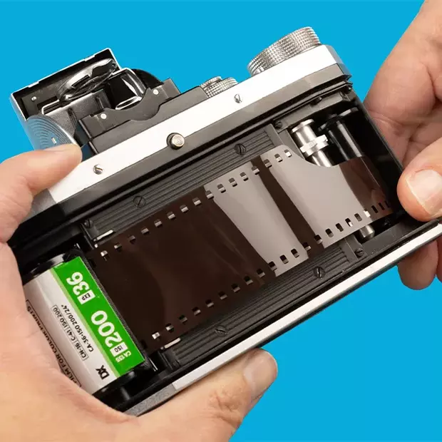 Ein Kleinbildfilm wird sorgfältig in eine Kamera eingelegt, nachdem das Gehäuse entfernt wurde.