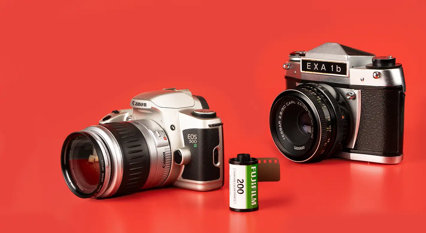 Eine Canon und eine Exa Analogkamera stehen neben einem Fuji Kleinbildfilm, bereit für analoge Fotografieabenteuer.