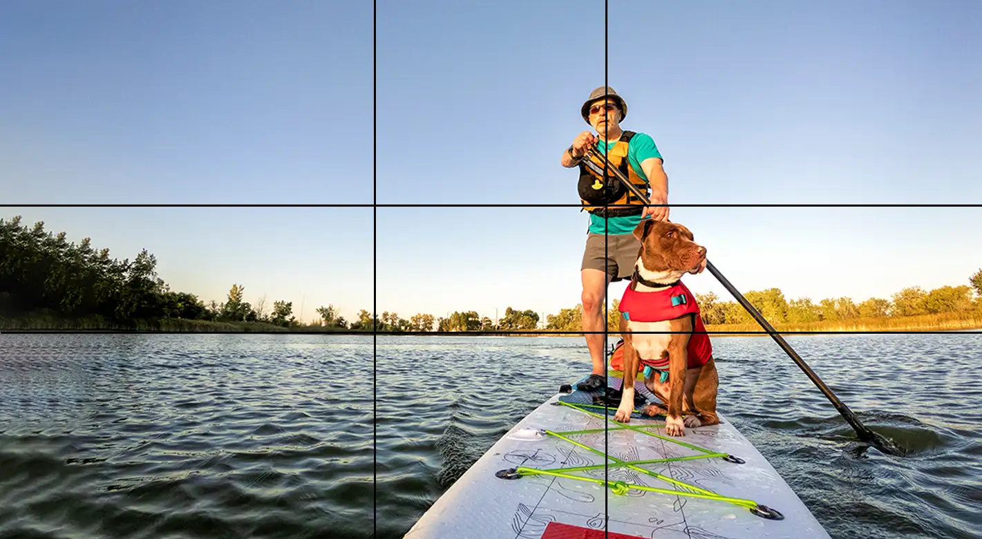 Bildanordnung nach dem Raster des goldenen Schnitts: Fotografie von einem Mann und einem Hund auf einem SUP.