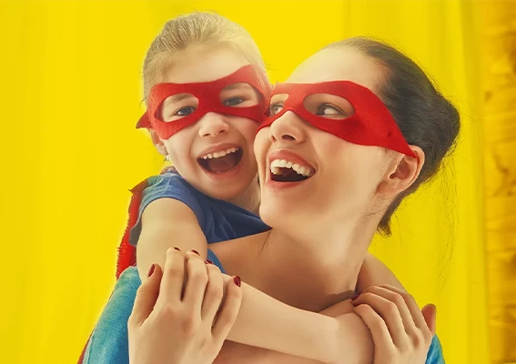 Fotoprodukte als kreative Geschenkideen für besondere Momente Mutter und Kind mit roten Superheldenmasken lachen gemeinsam vor gelbem Hintergrund, kreative Geschenkidee mit Fotoprodukten