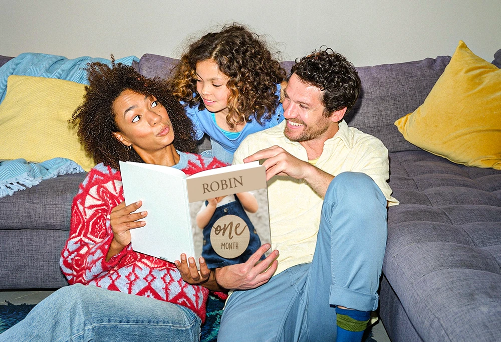 Fotoprodukte ORWO – Tipps und Ideen für dein persönliches Fotobuch Familie sitzt gemeinsam auf dem Sofa und schaut ein Fotobuch mit Erinnerungen durch.