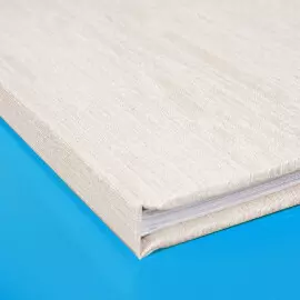 Fotobuch mit stilvollem Leinencover Eckansicht eines weißen Buches mit Leinencover auf blauem Hintergrund. Der Hardcovereinband des Buches wird mit echtem Leinen überzogen.
