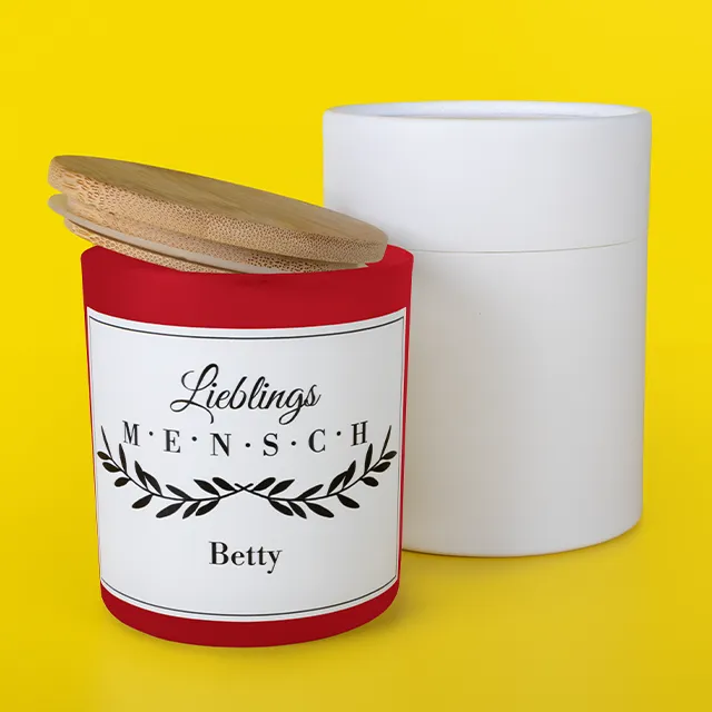 Duftkerze, personalisiert mit Spruch Eine Duftkerze, personalisiert mit Spruch. Der Bambusdeckel liegt schräg auf der Kerze, dahinter steht eine weiße Verpackung.